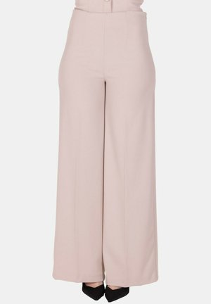 Pantaloni beige a vita alta e gamba larga indossati con scarpe nere con punta appuntita, mostrati dalla vita ai piedi su sfondo neutro.