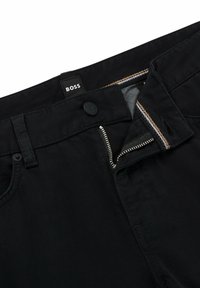 Pantalones negros con cierre de botón y cremallera. Presentan detalles de costura y una etiqueta que dice "BOSS" en la cintura. Material de mezcla de algodón.