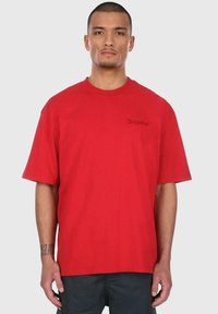 Rød kortærmet T-shirt lavet af bomuld med en afslappet pasform. Har broderet logo på venstre bryst og rund halsudskæring.