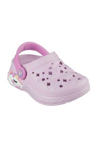 Zueco de color lila claro con un diseño estampado y agujeros de ventilación, presenta una correa rosa y un acento de unicornio en el costado.