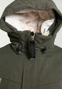 Chaqueta de invierno con capucha de color verde oscuro con forro de piel sintética beige y cordones ajustables negros en la capucha, que cuenta con una cremallera central con tirador negro.