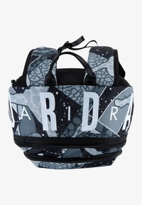 Μαύρο και γκρι σακίδιο με αφηρημένα μοτίβα, μεγάλα λευκά γράμματα, διπλά φερμουάρ και επενδεδυμένους ιμάντες ώμου. Διαθέτει δύο επάνω λαβές.