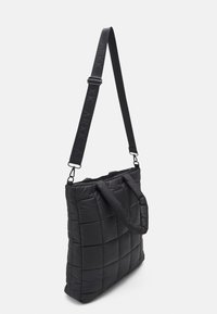 Czarna pikowana torba na ramię z wyściełanymi uchwytami i regulowanym paskiem na ramię, z wypukłym logo na jednolitym tle.