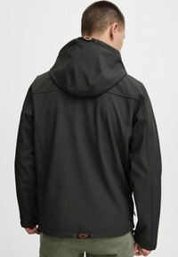 Sort softshell-jakke med hætte, der har et strømlinet design og justerbar snor. Tekstureret stof og subtile syninger er synlige.