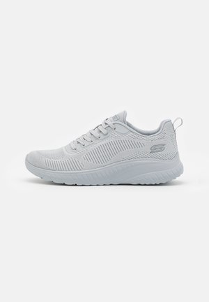 Jasnoszare sportowe buty Skechers z siateczkową cholewką, sznurowanym zapięciem, amortyzowaną podeszwą i pętelką na pięcie, przedstawione w widoku z profilu.