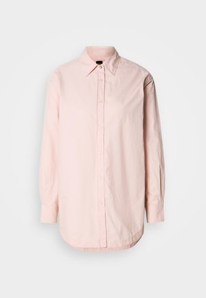 Helles rosa Hemd mit Knopfleiste, spitzem Kragen, langen Ärmeln und abgerundetem Saum. Verfügt über eine dezente Textur und ein kleines besticktes Detail.