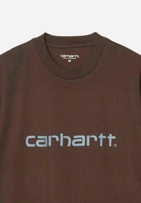 T-shirt in cotone marrone con il logo "carhartt" di colore azzurro chiaro in evidenza sul petto. Design classico con collo a giro e maniche corte.
