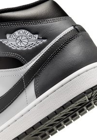 Zapatillas de cuero en blanco y negro con una textura suave, que presentan un prominente logo de 'Air Jordan', una entresuela blanca y una suela negra con patrón.