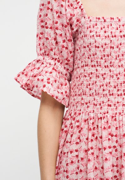 Ροζ φόρεμα με κόκκινο φρουτώδες και κυματιστό μοτίβο, με φουσκωτό μανίκι με ελαστικό τελείωμα και μπούστο με σφηκοφωλιά.