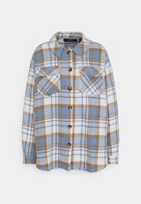 Camicia a quadri blu, bianca e marrone con due tasche sul petto e colletto classico, esposta su uno sfondo bianco.