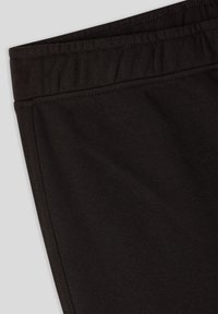 Pantaloni neri in cotone con cintura elastica, caratterizzati da una texture liscia e dettagli di cucitura sottili lungo le cuciture.
