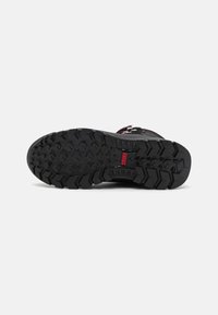Black trekking shoe sole with a textured rubber pattern, featuring deep treads for grip and red accent branding in the center.