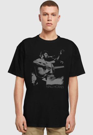 Black cotton t-shirt featuring a graphic print of a man playing guitar against a cloudy background, with "NIALL HORAN" text at the bottom.