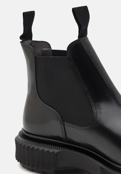 Botas Chelsea de cuero negro con paneles elásticos, tiradores y suela de goma texturizada que presenta profundas ranuras para mayor tracción.