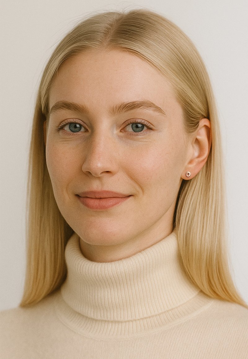 Porträtt av en person med långt, rakt blont hår, iklädd en beige polotröja. Enkla studsörhängen kompletterar looken.