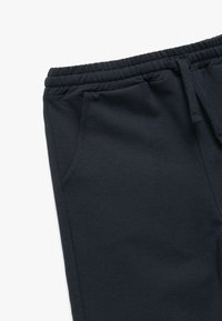 Marineblå sweatpants lavet af en blanding af bomuldsstof, med snor i taljen, sidelommer og en glat tekstur.