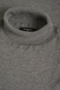 Pilkas golfo megztinis iš minkštos megztos medžiagos, su ribotu apykakle ir be siūlių, suteikiančių lygią apdailą. Matomas prekės ženklo ženklas.