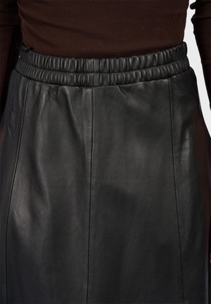 Jupe en cuir noir avec une taille élastique, texture lisse et design simple avec des coutures verticales pour un look ajusté.