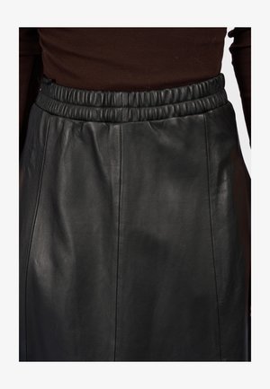 Gonna nera in pelle con vita elastica, texture liscia e design semplice con cuciture verticali per un look sartoriale.