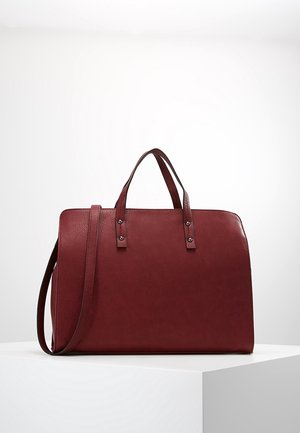 Viininpunainen nahkainen kauppakassi, jossa on kaksi yläkahvaa ja irrotettava olkahihna. Ominaisuuksiin kuuluu sileä pinta ja hopeansävyiset metalliosat.