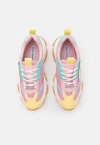 Zapatillas multicolores con un diseño de malla en rosa, azul y amarillo, cordones blancos y suelas de goma naranjas con una lengüeta trasera.