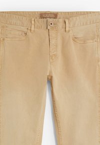 Pantalones de algodón beige con cierre de cremallera y botón, dos bolsillos delanteros y un diseño ajustado. Presentan una textura sutil y la marca Scalpers.