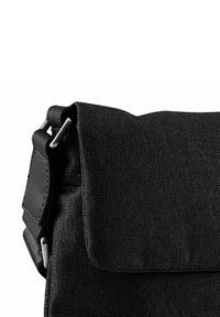 Borsa in tessuto nera con chiusura a patta, dotata di un accento in pelle a contrasto, hardware in metallo e una superficie in tessuto testurizzato.