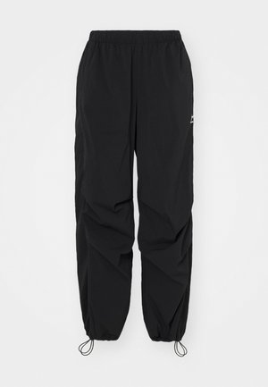 Black windbreaker pants with an elastic waistband, adjustable cuffs, and a slight sheen. Features a logo near the waistband. Breathable fabric.