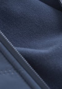 Granatowoniebieskie miękkie wnętrze z gładką teksturą i detalami zamka błyskawicznego, z równomiernym przeszyciem wzdłuż krawędzi.