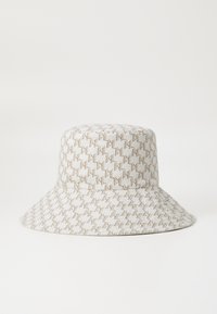 Bucket-hatt i ljusbeige tyg med ett vävt mönster av bruna zick-zack-linjer, med en bred skärm och en strukturerad kröne.