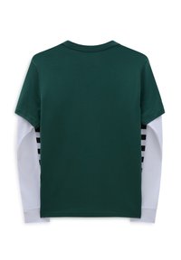 Groen T-shirt met korte mouwen, gedragen over een wit shirt met lange mouwen, met zwart gestreepte accenten op de witte mouwen.