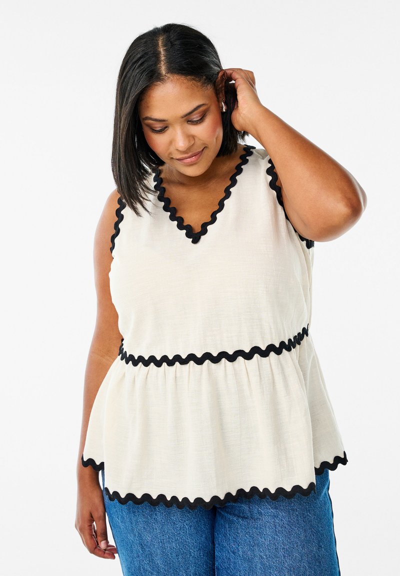 Bílý peplum top s černým vlnkovým lemováním podél výstřihu a pasu, vyFeaturing hladký povrch a výstřih ve tvaru V.