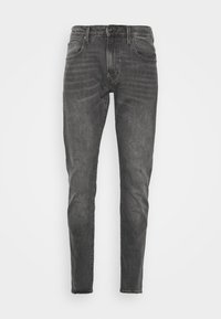 Jeans slim fit en denim gris oscuro, con un diseño clásico de cinco bolsillos, presillas para el cinturón y un ligero desgaste. Textura suave con un acabado liso.