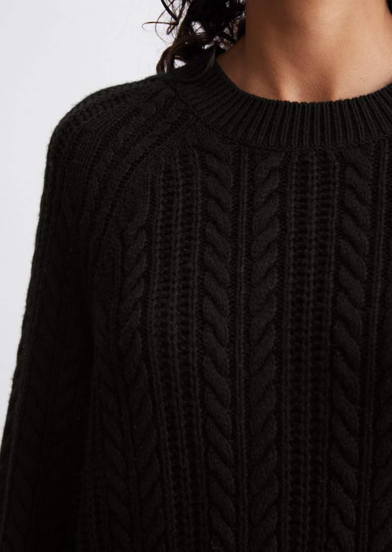 Schwarzer Strickpullover mit strukturiertem Zopfmuster, geripptem Kragen und langen Ärmeln, der aus einem gemütlichen Strickstoff besteht.