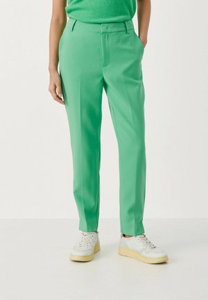 Groene op maat gemaakte broeken met zijzakken, recht model, gladde textuur en plooi-detail, gecombineerd met witte sneakers.