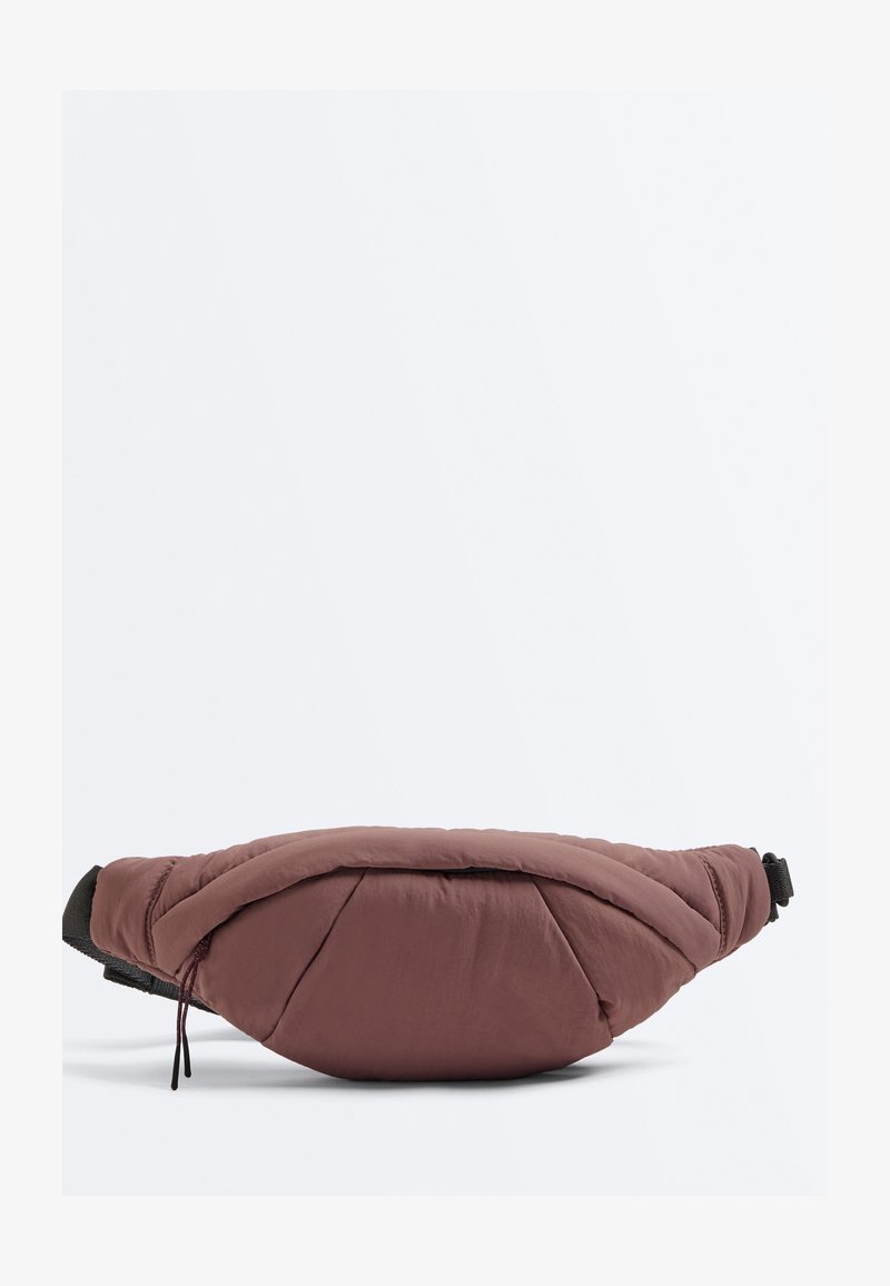 Sac banane marron matelassé avec une fermeture éclair et une sangle noire réglable, présenté sur un fond clair uni.