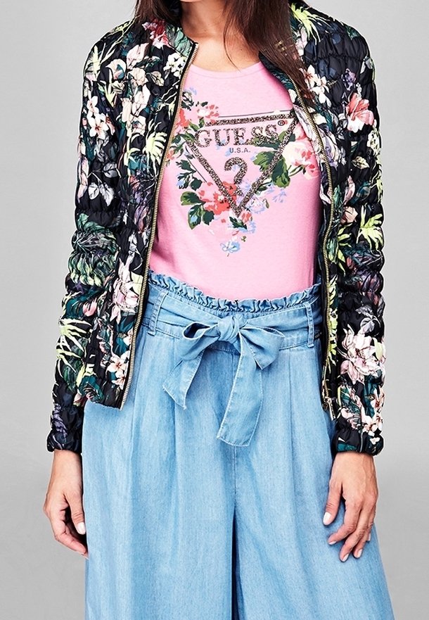 Zwarte bloemige bomberjack met een puffy textuur. Roze T-shirt met een decoratieve bloemige logo en lichtblauwe hoge taille, gestrikte broek.
