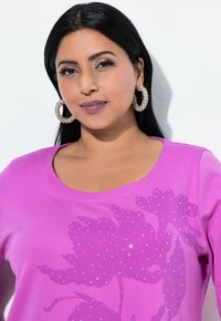 Lyserød bomulds t-shirt med rund halsudskæring, prydet med et blomstermotiv dekoreret med rhinsten for ekstra detaljer og tekstur.