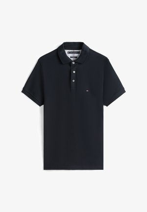 Polo azul-marinho feito de tecido texturizado, com uma pala de dois botões e um pequeno logotipo no peito. Mangas curtas.