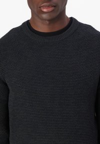 Ciemnoszary, dziany sweter z okrągłym dekoltem. Teksturowana powierzchnia z wzorem waflowym. Długie rękawy i luźny krój.