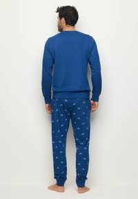 Blaues Baumwoll-Pyjama-Set mit einem Langarm-Oberteil und bedruckten Hosen, die kleine Fahrrad-Muster zeigen. Die Hosen haben elastische Bündchen und einen elastischen Taillenbund.