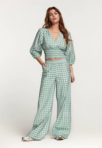Groen en roze patroon co-ord set bestaande uit een cropped top met pofmouwen en wijde broekspijpen, gemaakt van zacht, lichtgewicht stof.