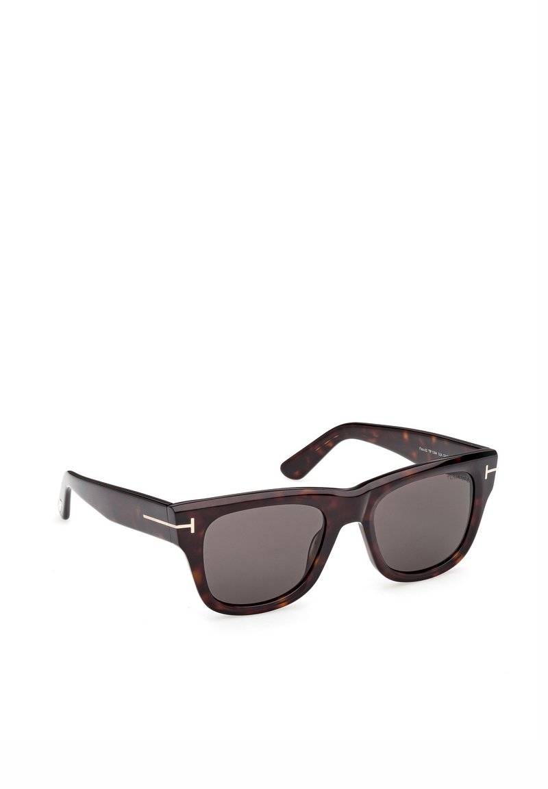 Lunettes de soleil écaille de tortue marron à la forme carrée, verres foncés et accents métalliques contrastants sur les branches, avec une finition lisse.