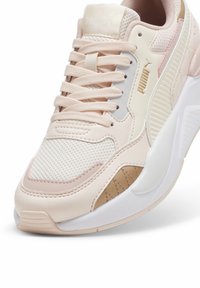 Baskets Puma combinant mesh et matériaux synthétiques en rose pâle, blanc et beige, avec des accents texturés et une semelle coussinée.