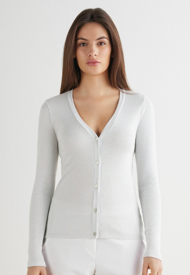 Jasnoszary kardigan prążkowany z dekoltem w serek, długimi rękawami i zapięciem na guziki z przodu. Gładka faktura z subtelnymi kontrastującymi akcentami guzików.