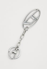 Silver metal keychain featuring an oval shape with cut-out design, connected by a chain to a circular keyring with a latch.