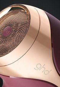 Gros plan sur un rasoir à tissu rose doré et bordeaux avec un maillage métallique perforé et le logo "99%" sur la surface métallique.