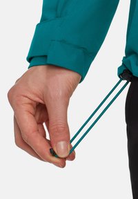 Bottone della manica della giacca turchese con cordino regolabile. Mano che stringe due corde teal, con un blocco di corda nero. Tessuto liscio e design strutturato.