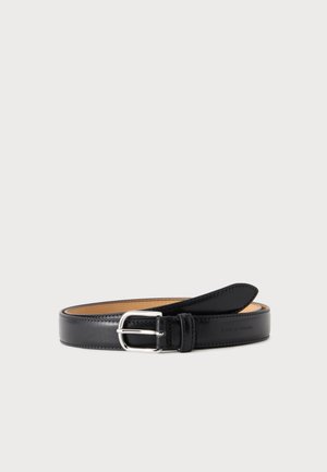 Ceinture en cuir noir avec boucle rectangulaire argentée, roulée avec la boucle vers l'avant sur un fond clair uni.