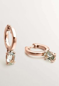 Pendientes de aro en oro rosa con un acabado pulido, que cuentan con un cristal ovalado transparente colgante sujeto por un engaste de garra.
